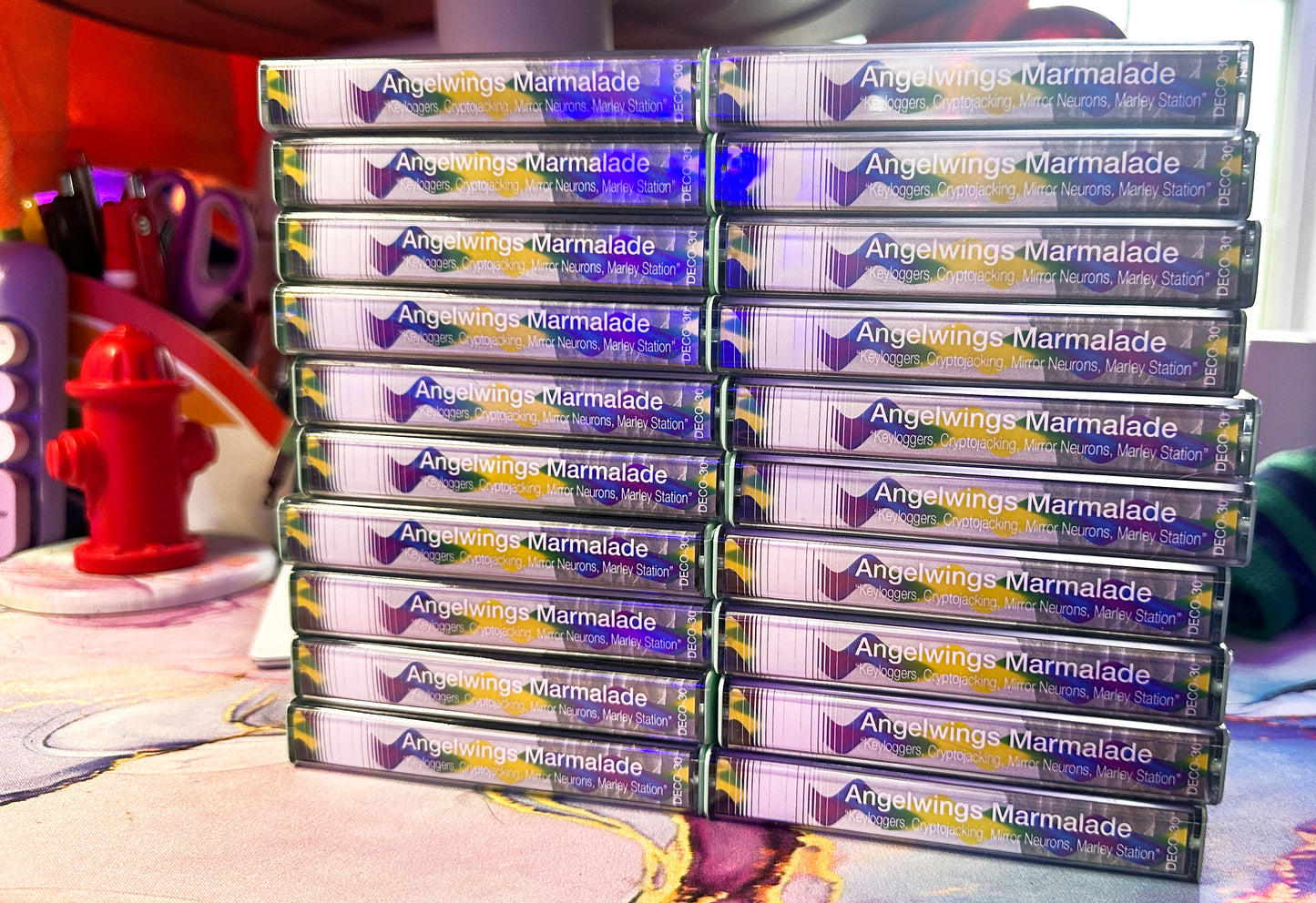 Multiple cassette boxes of Angelwings Marmalade stacked on a colorful background