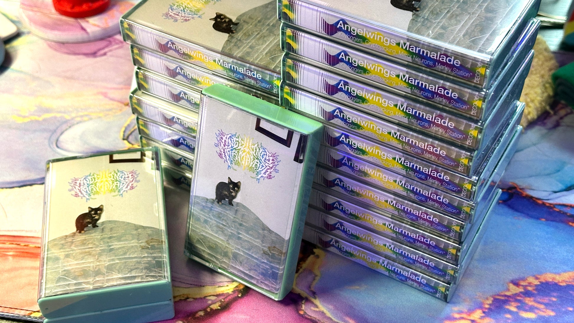 Stacks of 'Angelwings Marmalade' cassette boxes on a colorful surface